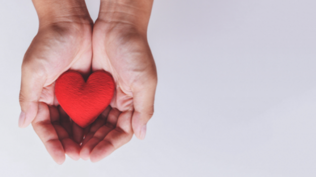 Hands holding a red felt heart. 